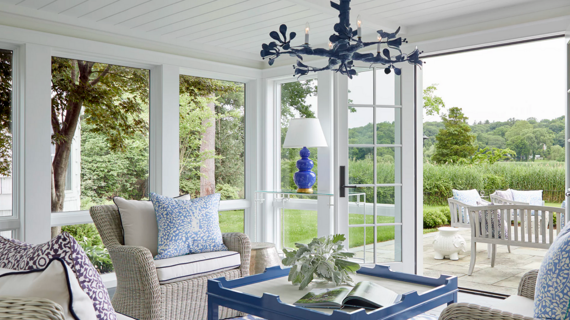 Bright sunroom interior with wicker seating, blue accents, and garden views